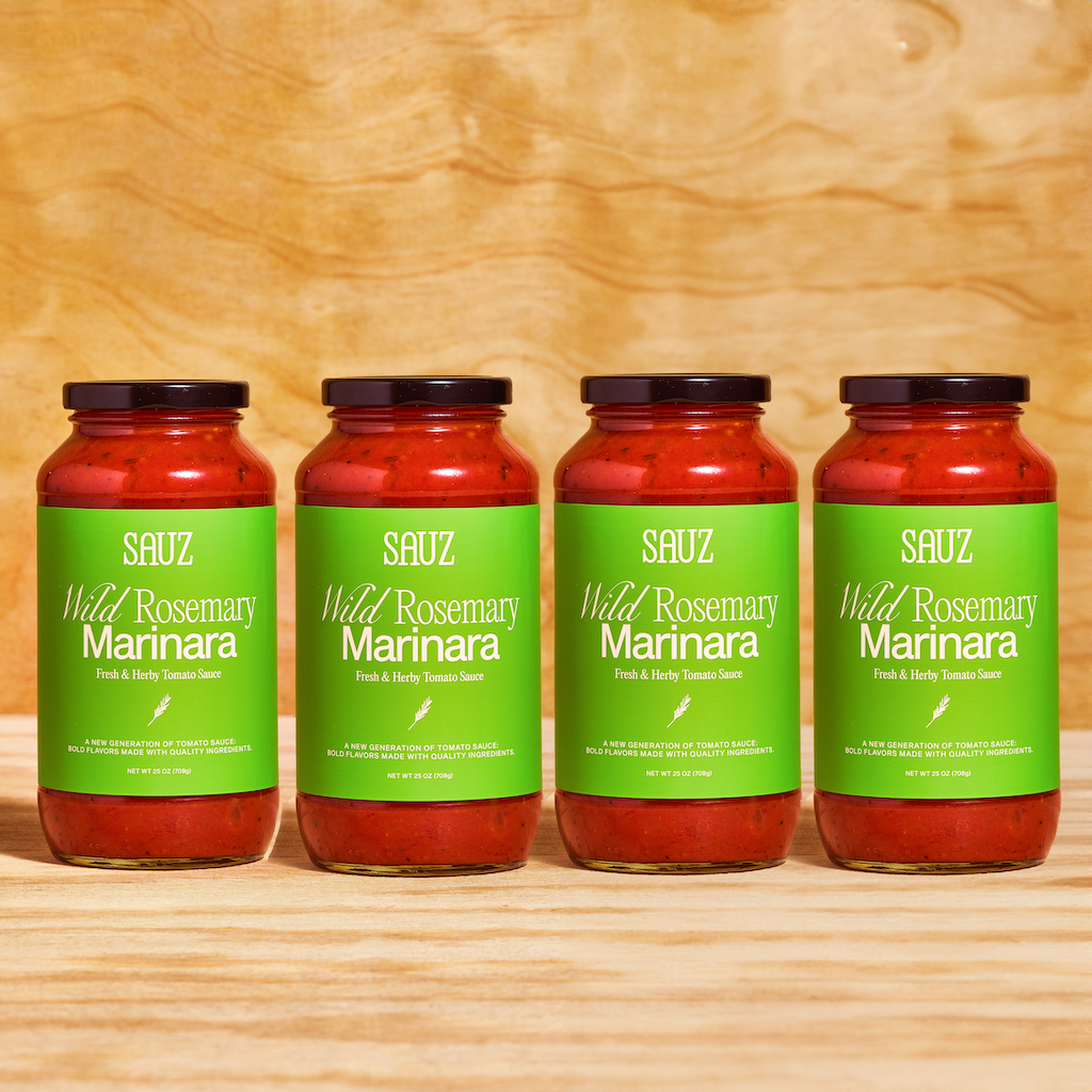 Four jars of Sauz Wild Rosemary Marinara displayed side by side against a wooden background, featuring vibrant green labels and a fresh, herby tomato sauce inside